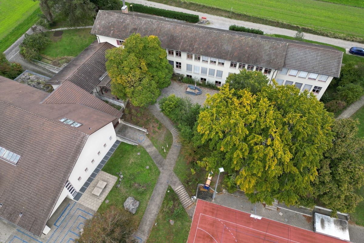 Schulanlage zwischen Rudolfingen und Trüllikon. Die Turnhalle (links) ist nicht tangiert, im Schulhaus (oben) wird unter anderem eine neue Raumaufteilung vorgenommen, um Gruppenräume zu erhalten. Der Zwischentrakt wird zum Verwaltungstrakt mit Büro für Schulleitung und neu Sekretariat.